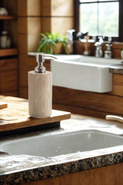 Close-up of the rainbow sandstone soap dispenser with stainless steel pump, placed beside a farmhouse sink in a warm, rustic kitchen.