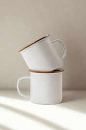 Two stacked eggshell enamel cups with bronze rim in morning light”