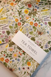 Folded Botanist Linen Tea Towel showing botanical details and colorful wildflowers.