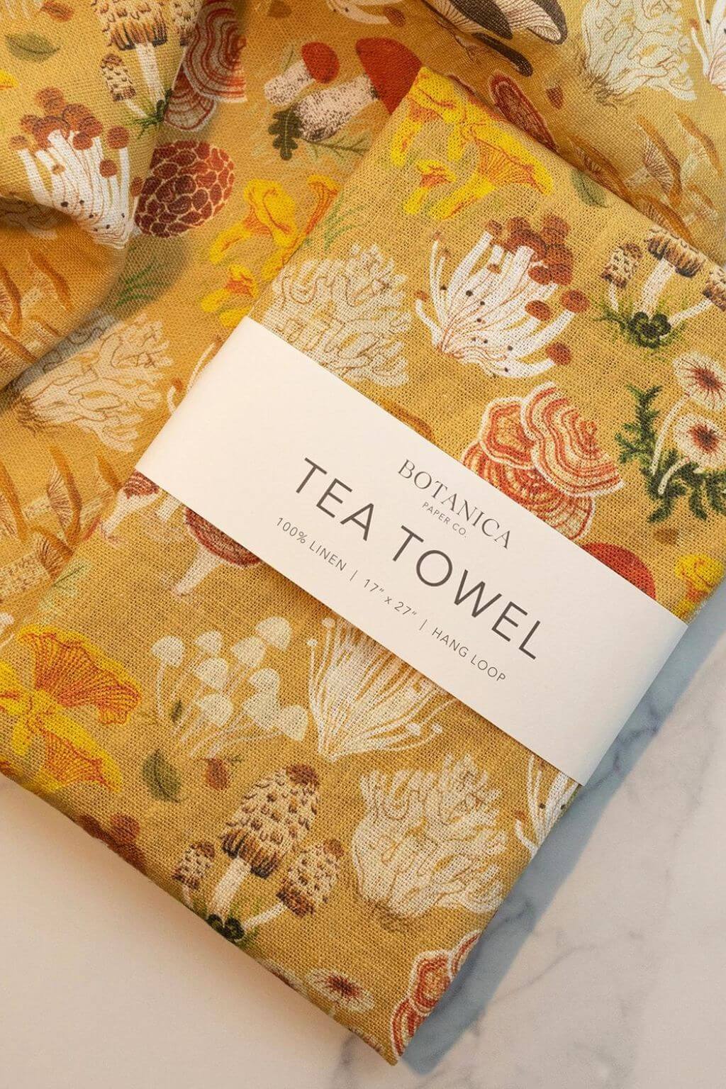 Folded Mushroom Melange Linen Tea Towel showing vibrant forest mushroom illustrations.