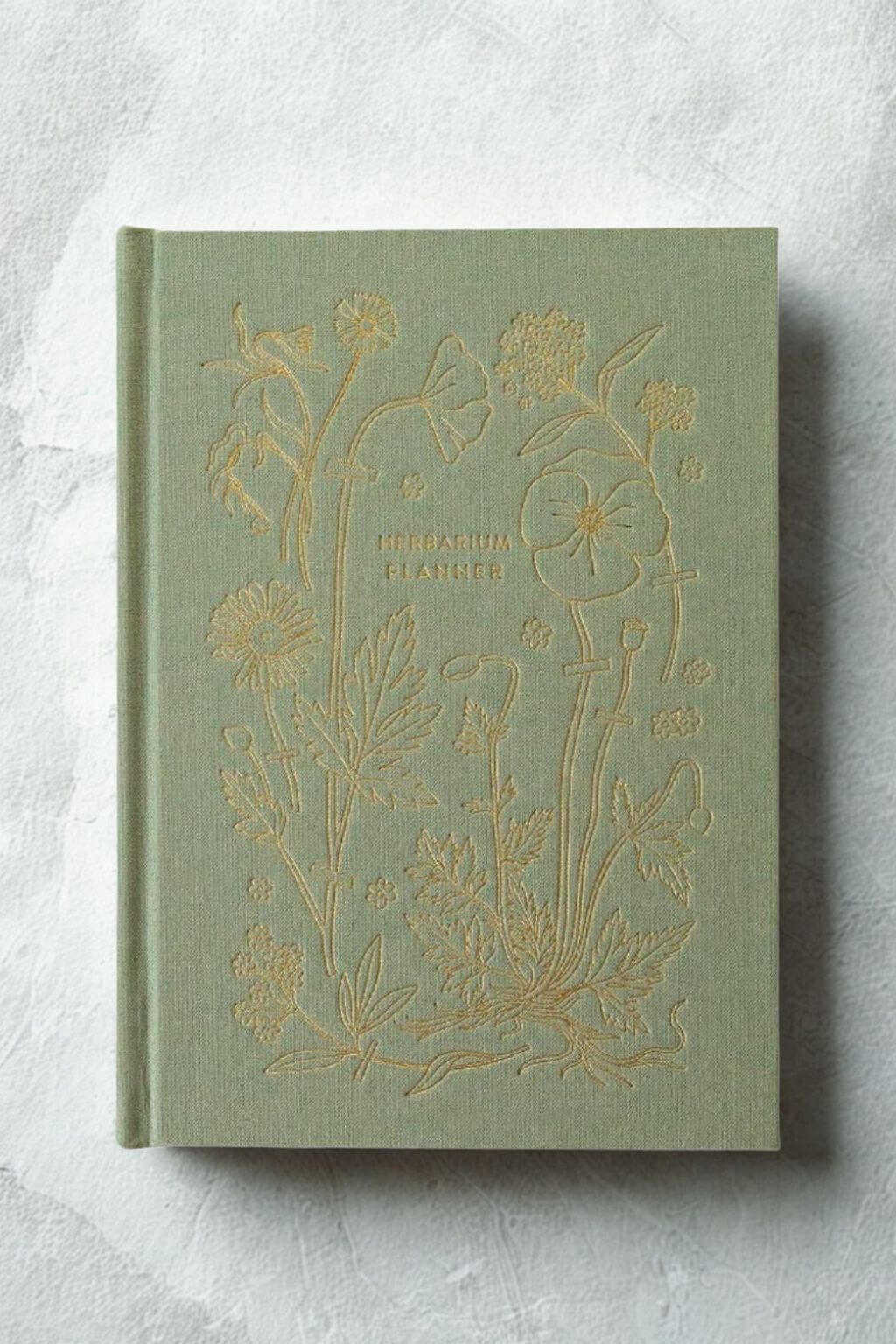 Green Herbarium Planner with gold embossed floral design on a textural light gray background