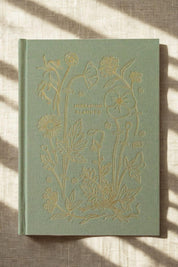 Green Herbarium Planner with floral design on a linen surface with dramatic shadows