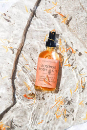 Sunrise Body Oil floating in clear water with calendula petals.