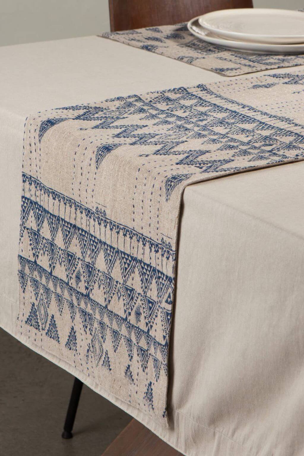 Table setting with a blue geometric patterned Enigma Table Runner on a linen tablecloth.