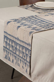 Table setting with a blue geometric patterned Enigma Table Runner on a linen tablecloth.