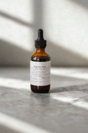 Amber glass dropper bottle of Skip the Shot tincture by Evergreen Apothecary on stone surface with soft sunlight