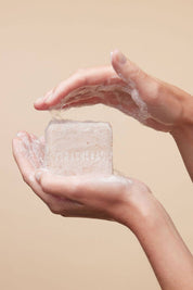Hands holding Fer à Cheval Gentle Cleansing Soap with lathered foam, close-up on natural texture.