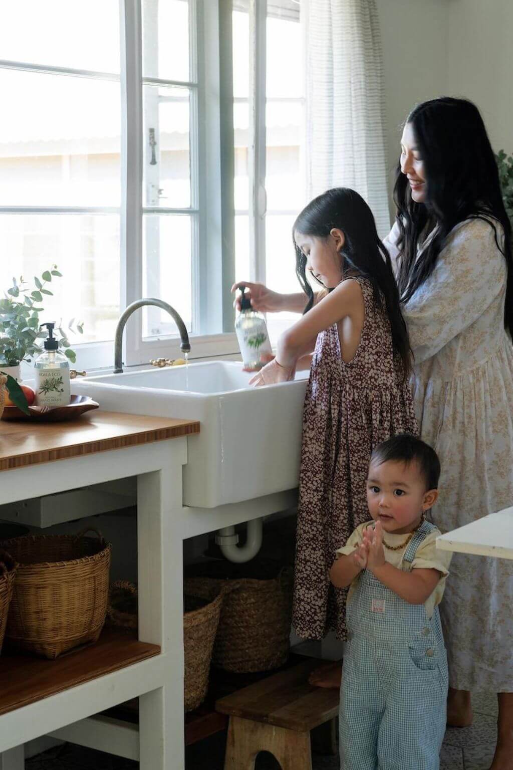 A mother and her two young children washing their hands in the kitchen sink with Koala Eco Natural Hand Soap