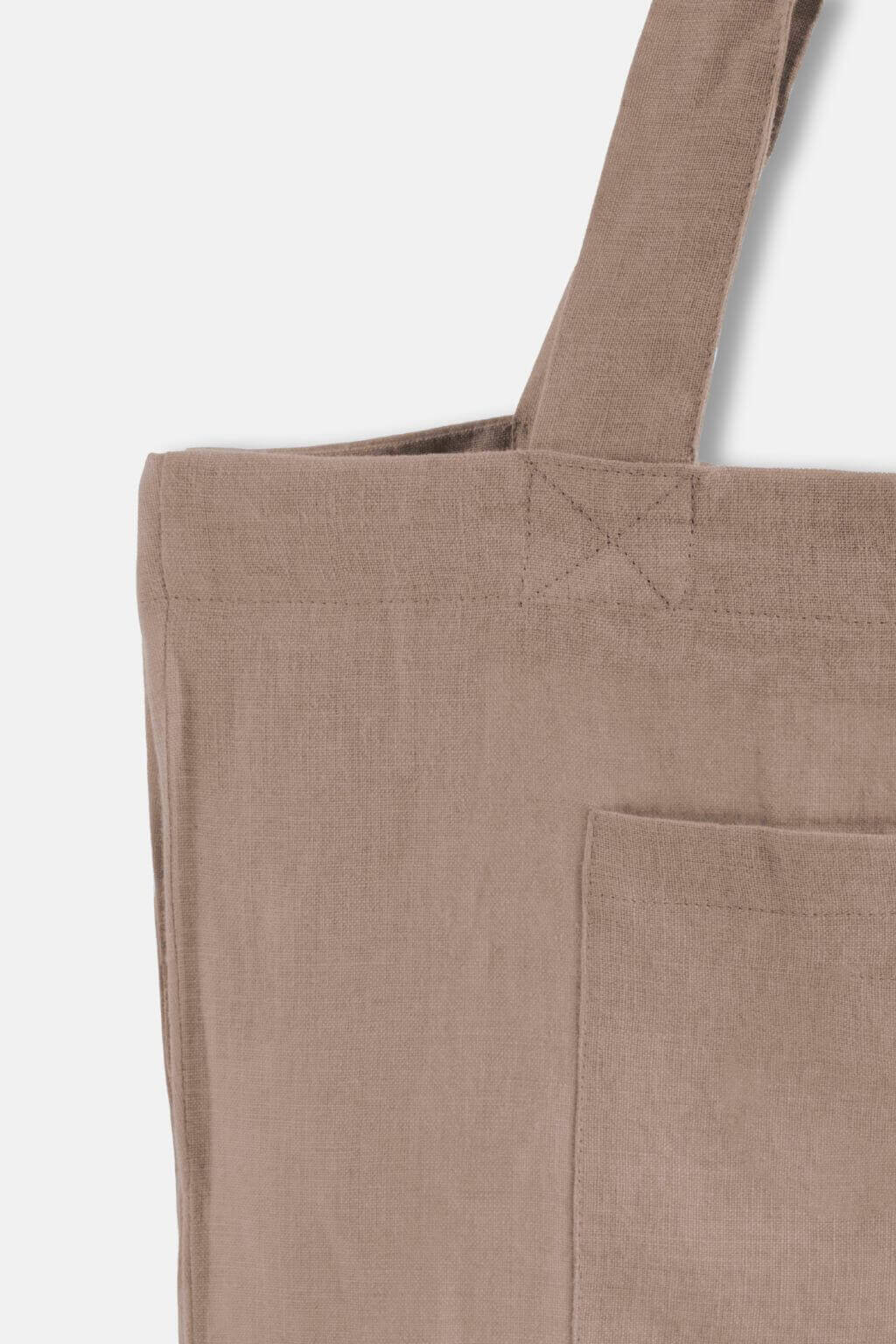 Close-up detail of sandy beige linen tote bag and handle stitching.