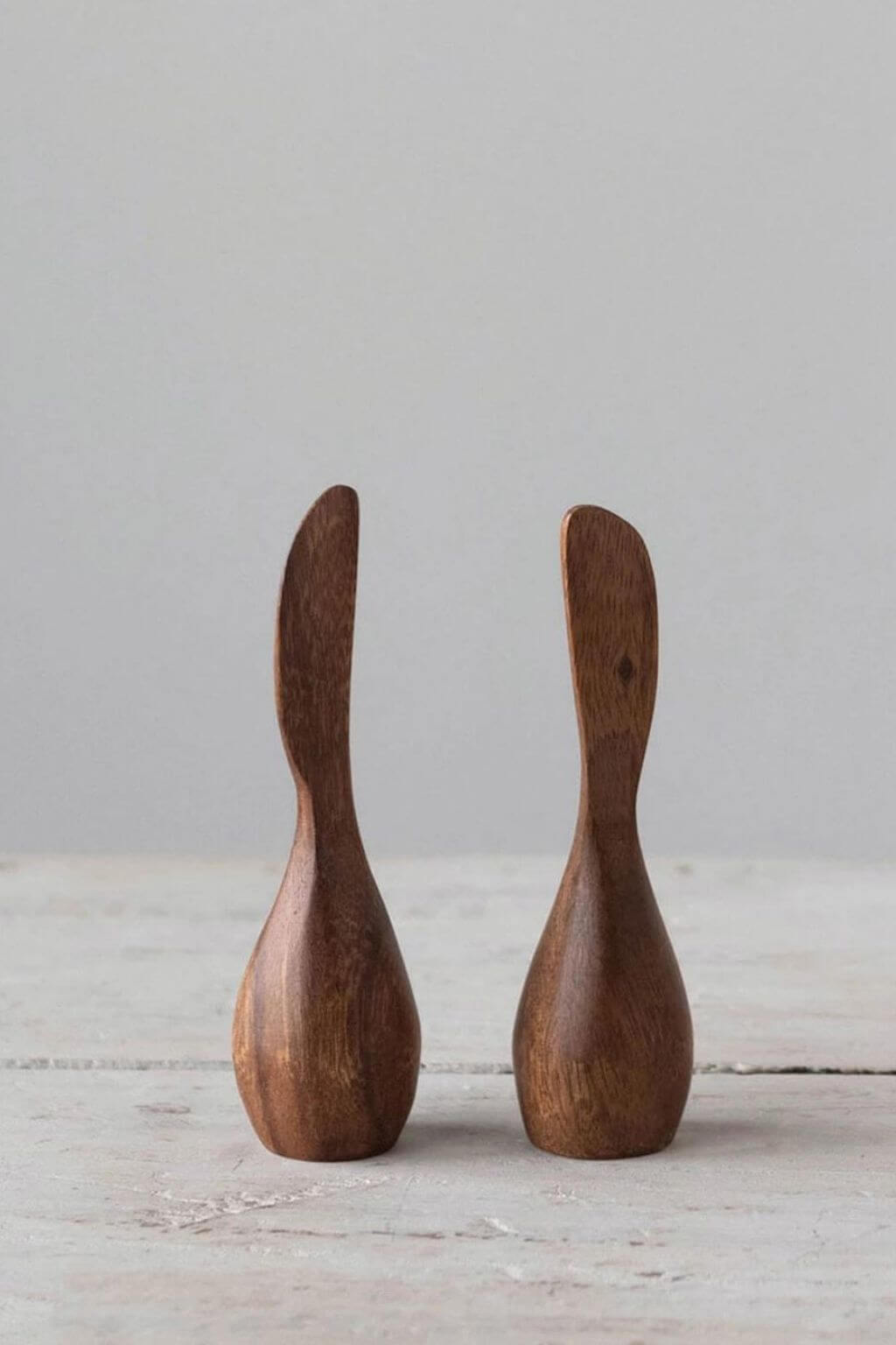 Pair of standing acacia wood canapé knives displayed on neutral tabletop.
