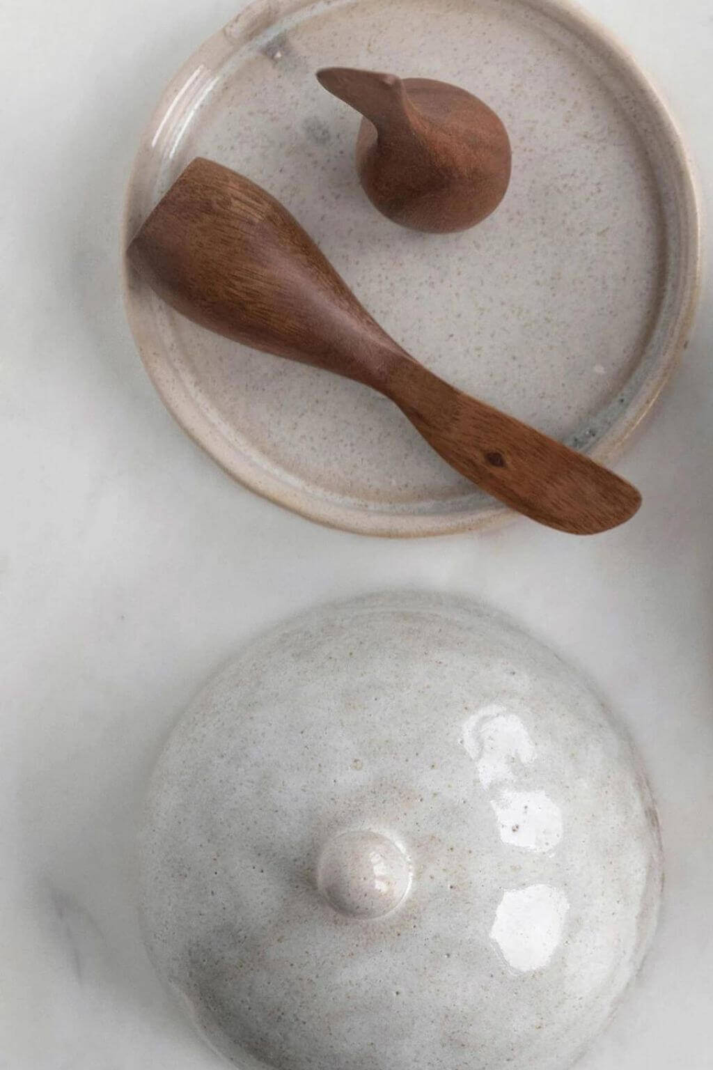 Acacia wood canapé knife resting on ceramic butter dish.