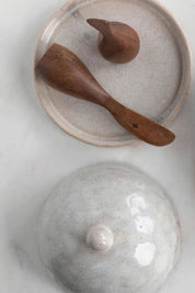 Acacia wood canapé knife resting on ceramic butter dish.