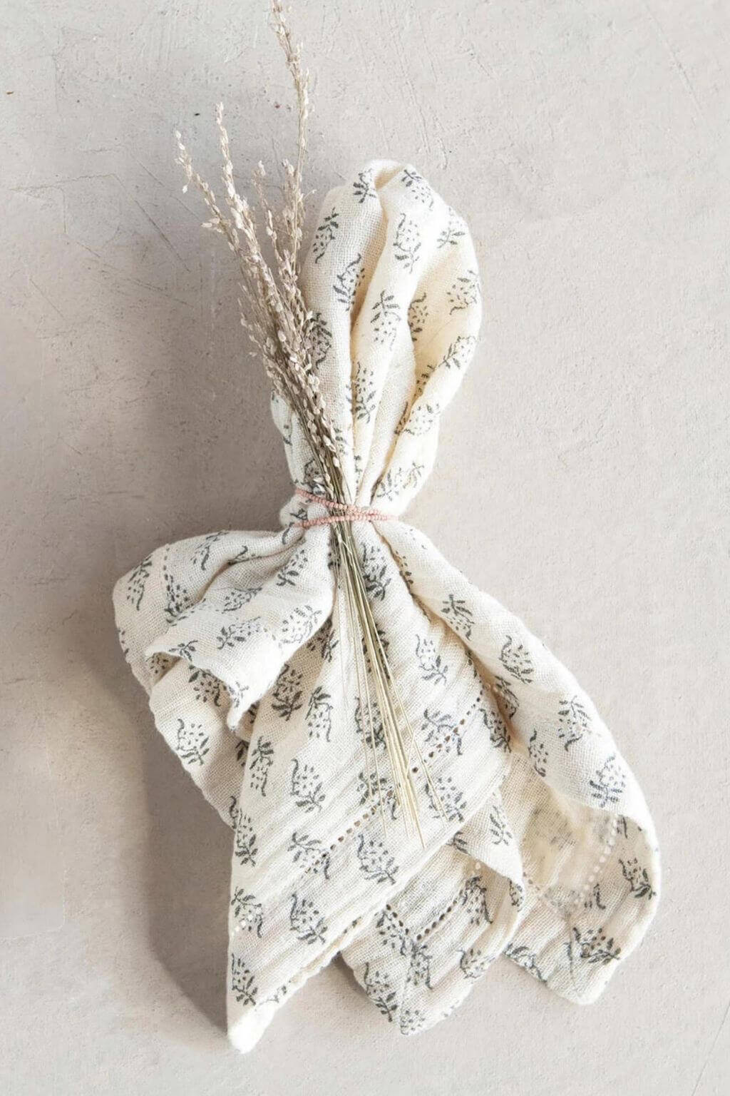 Folded napkins displayed with dried flowers tied in linen ribbon.