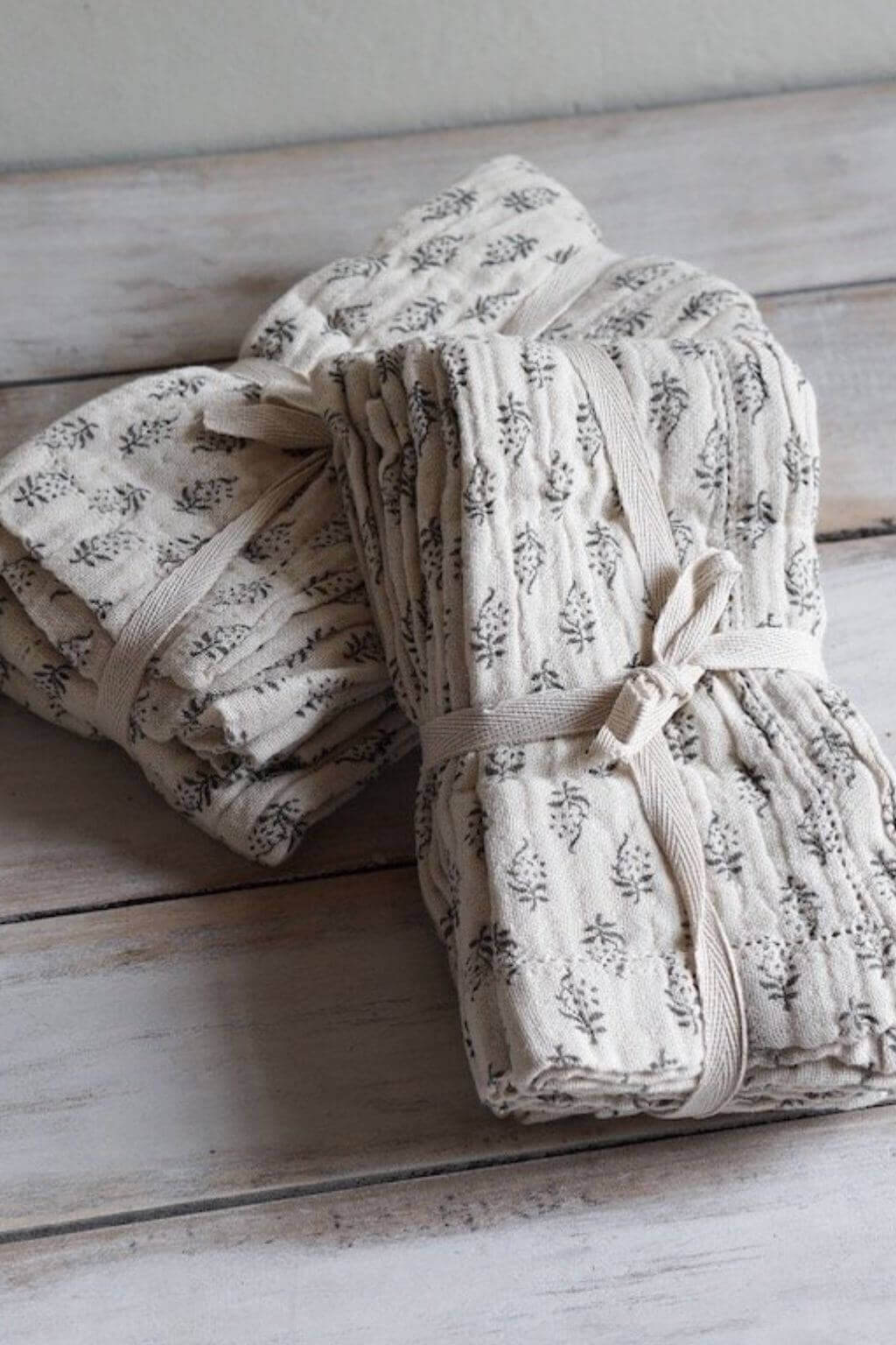 Two Scandinavian floral cotton napkin bundles arranged side by side.