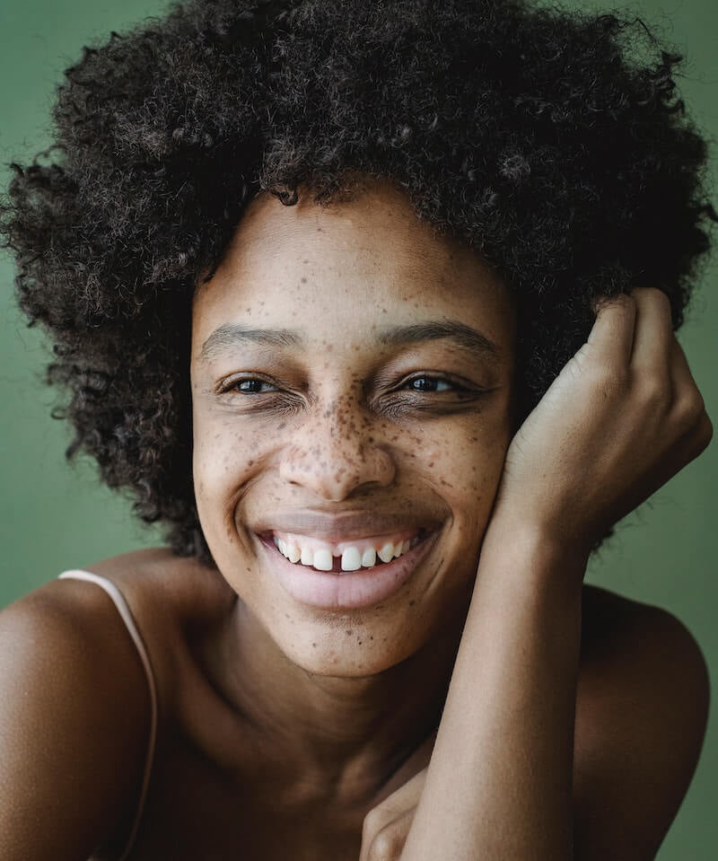Cultiverre : Bath + Beauty Colllection - Beautiful Smilling Black Woman against rich green background