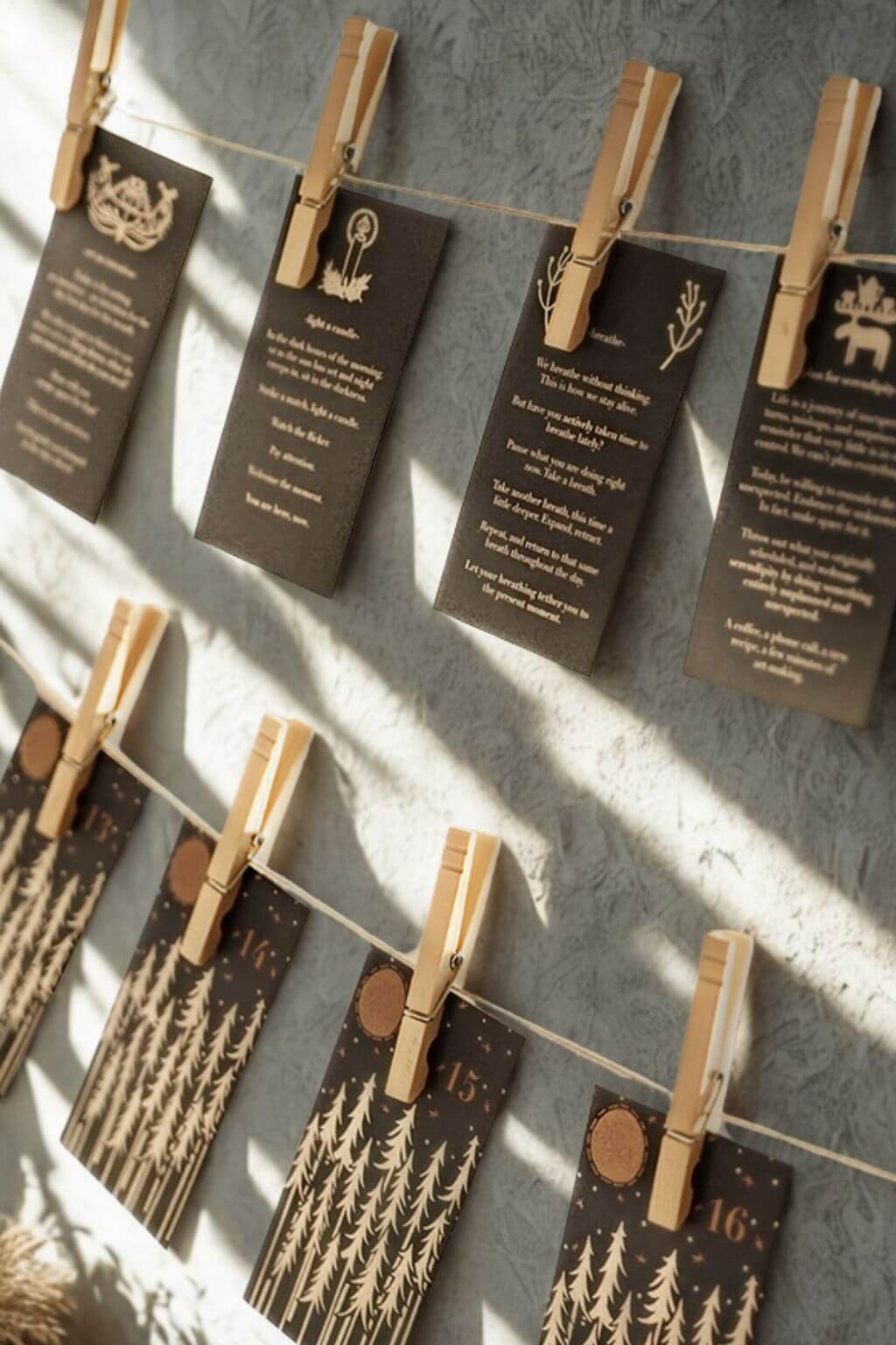 Set of Advent calendar cards hung on twine with clothespins, each printed with gold trees and daily mindfulness prompts.