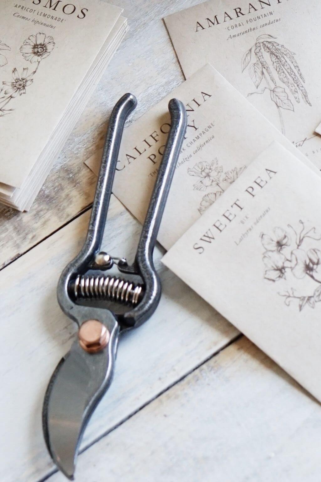 Pruner on a wooden surface with botanical-themed cards in the background