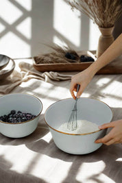 Whisking ingredients in enamel mixing bowl with berries beside