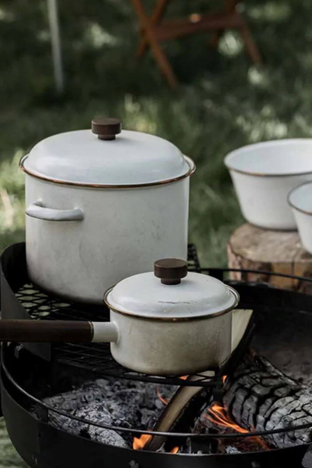 Barebones enamel cookware set over campfire