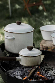 Barebones enamel cookware set over campfire