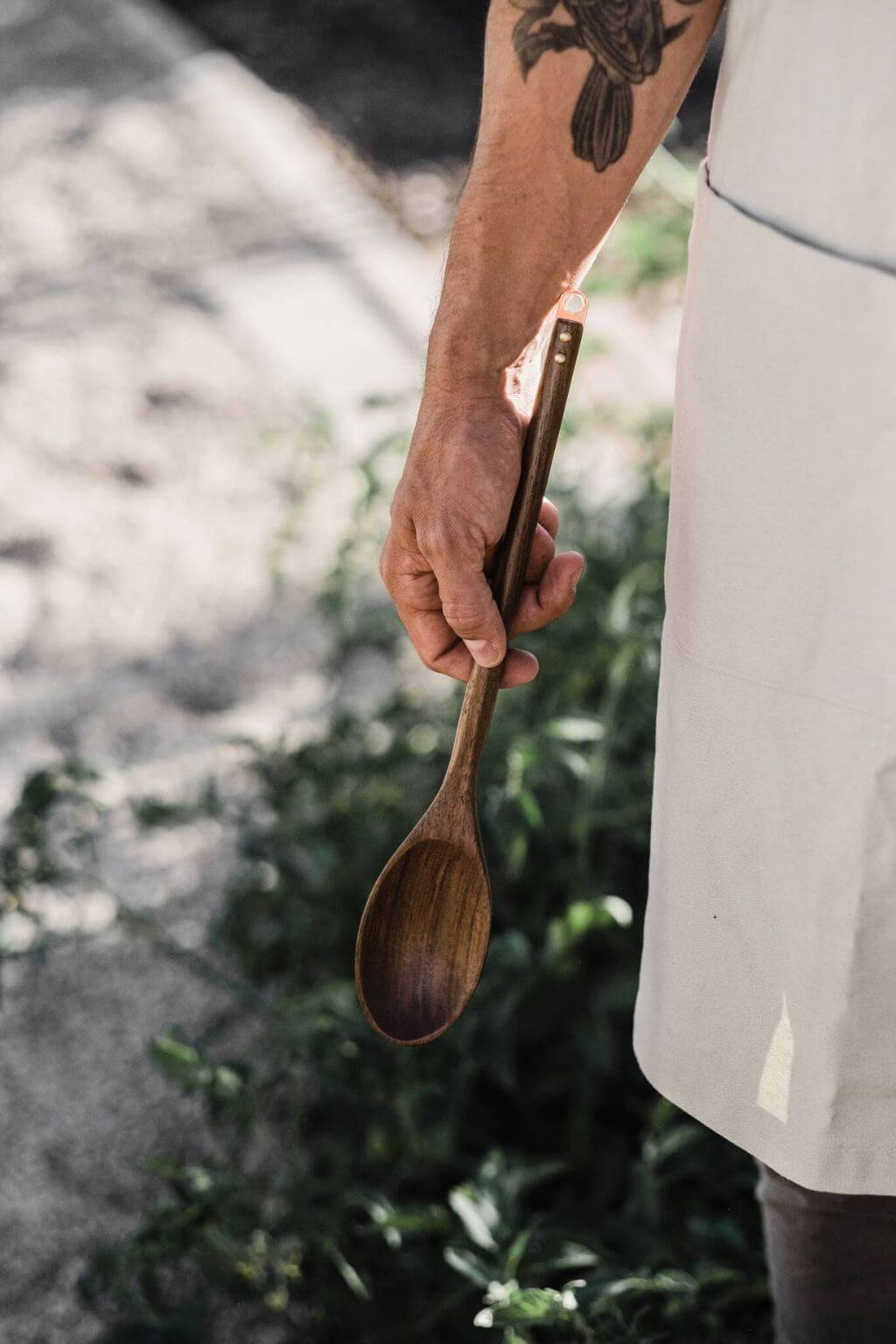 Black walnut wooden spoon held in hand outdoors