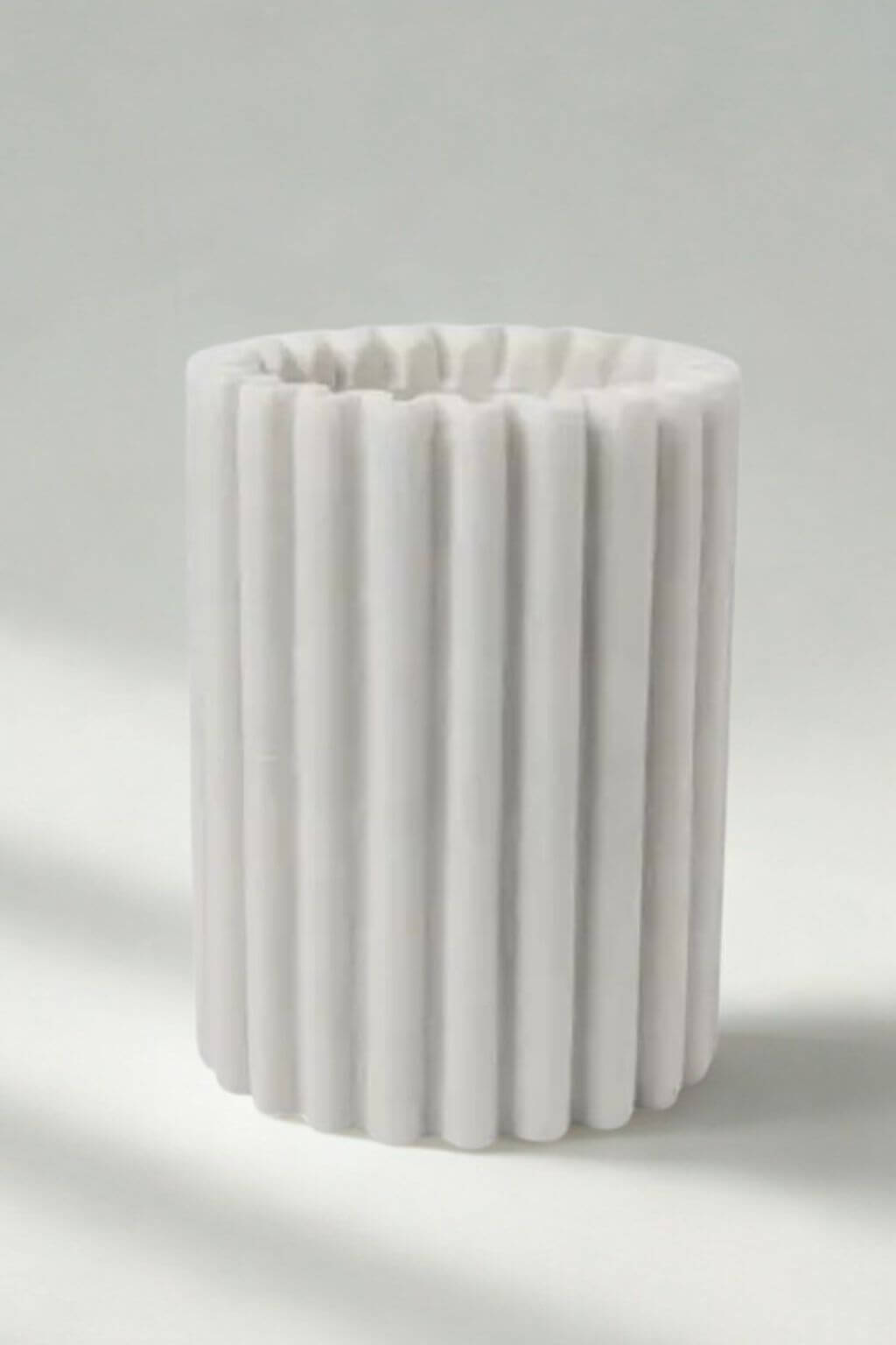 Handcrafted marble wine chiller in luminous white stone with soft vertical ridges.