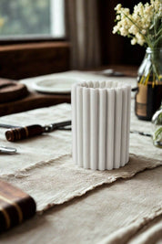 White marble bottle holder with fluted design on rustic linen table setting.