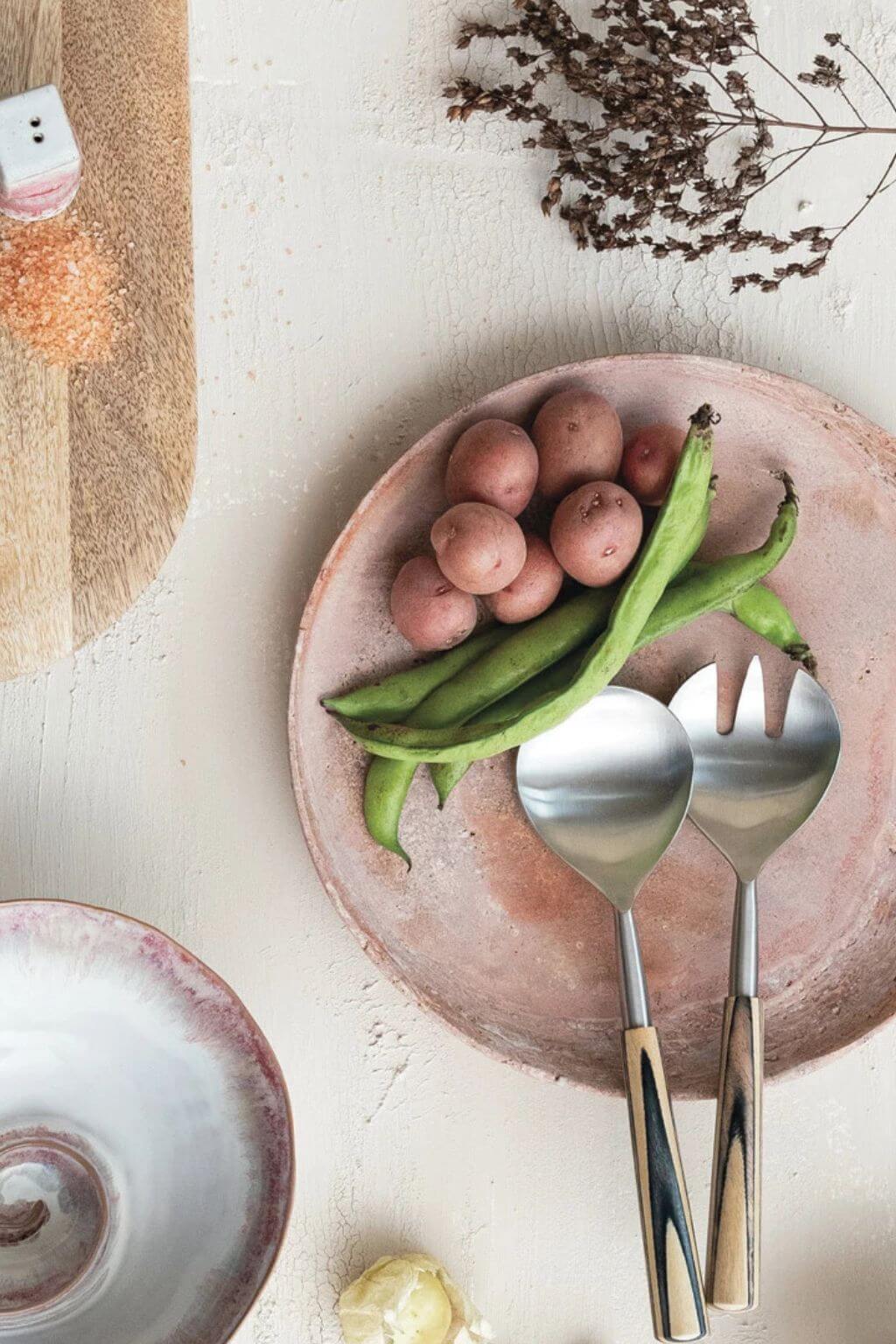 Handcrafted red travertine tray with potatoes and green beans on neutral linen table