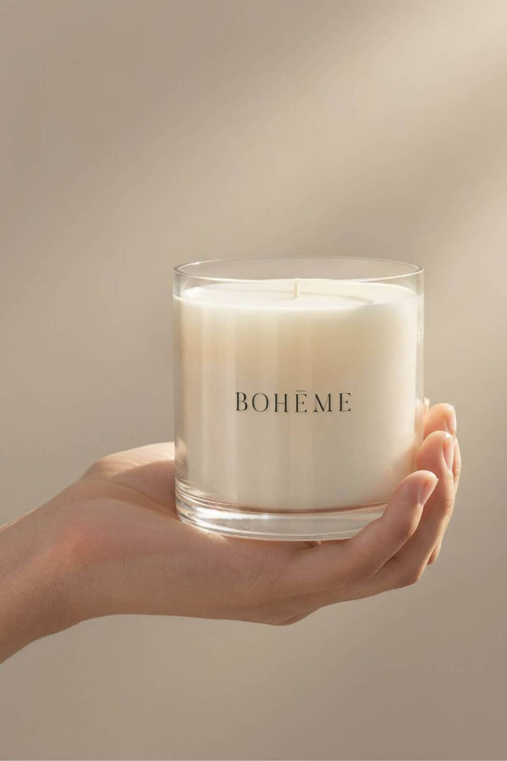 Hand holding a Bohème candle in clear glass, highlighting minimalist design and creamy soy wax