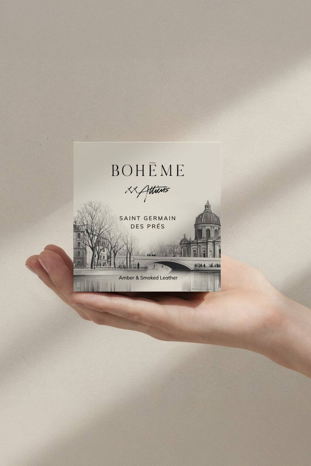 Hand holding Bohème Saint-Germain-des-Prés candle box, featuring Parisian architecture illustration