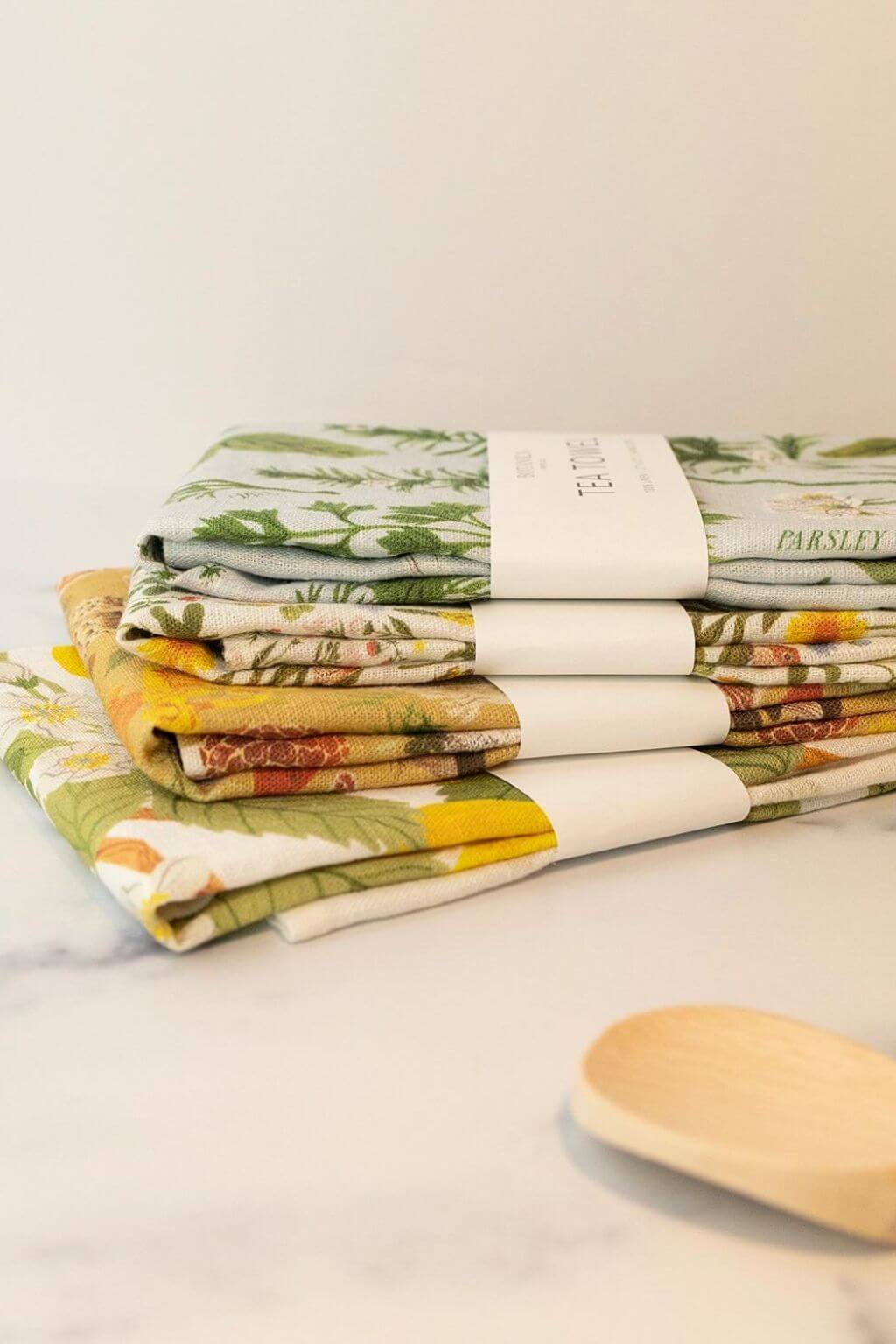 Stack of illustrated linen tea towels by Botanica Paper Co. including Herb Garden design.