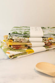Stack of illustrated linen tea towels by Botanica Paper Co. including Herb Garden design.