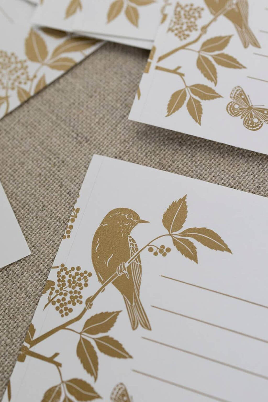 Close-up of gold foil bird and butterfly design on uncoated white gift labels.