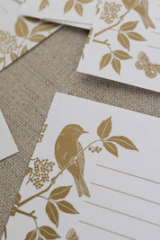 Close-up of gold foil bird and butterfly design on uncoated white gift labels.