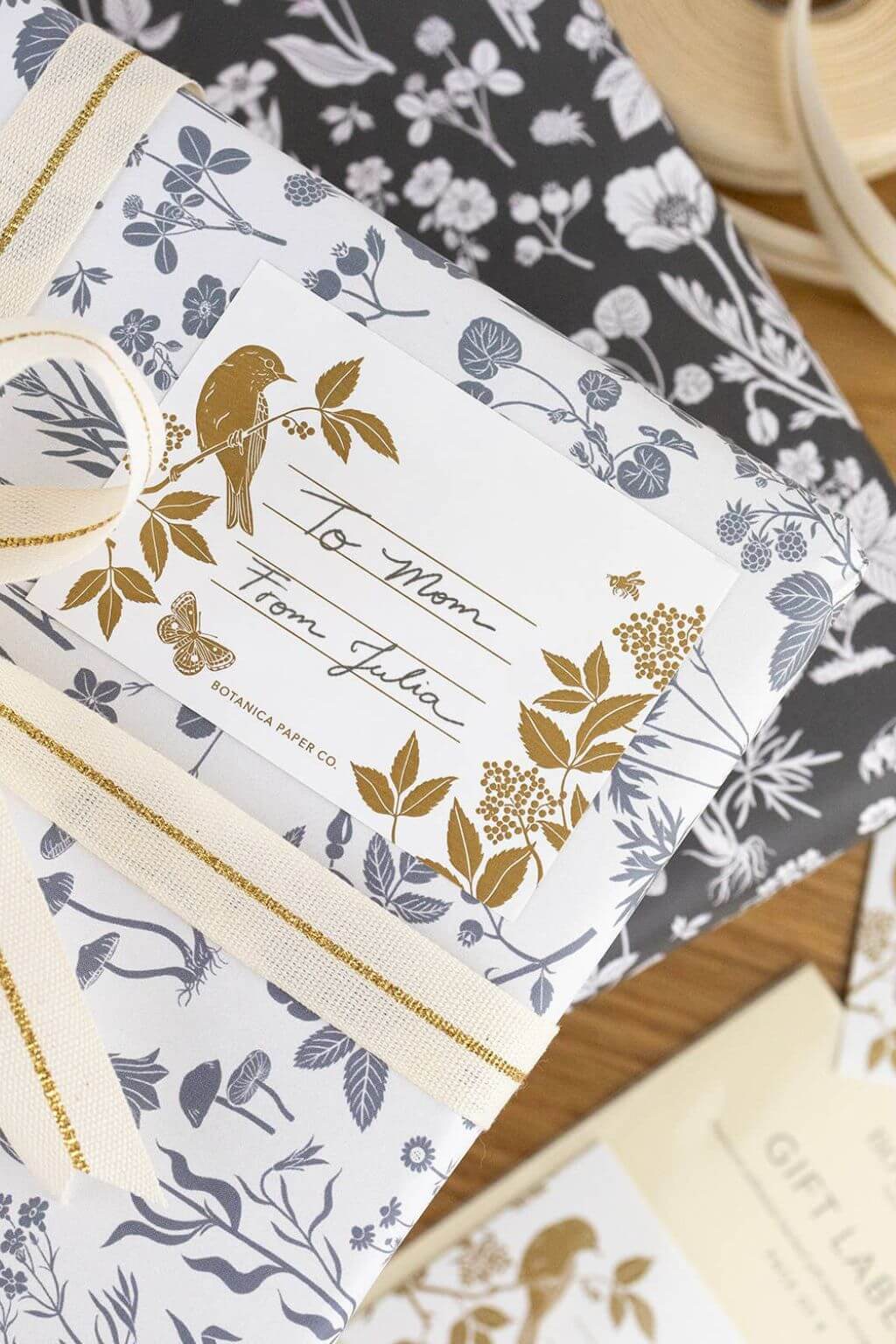 Gift wrapped in botanical paper with gold-printed Meadow label tied with ribbon.