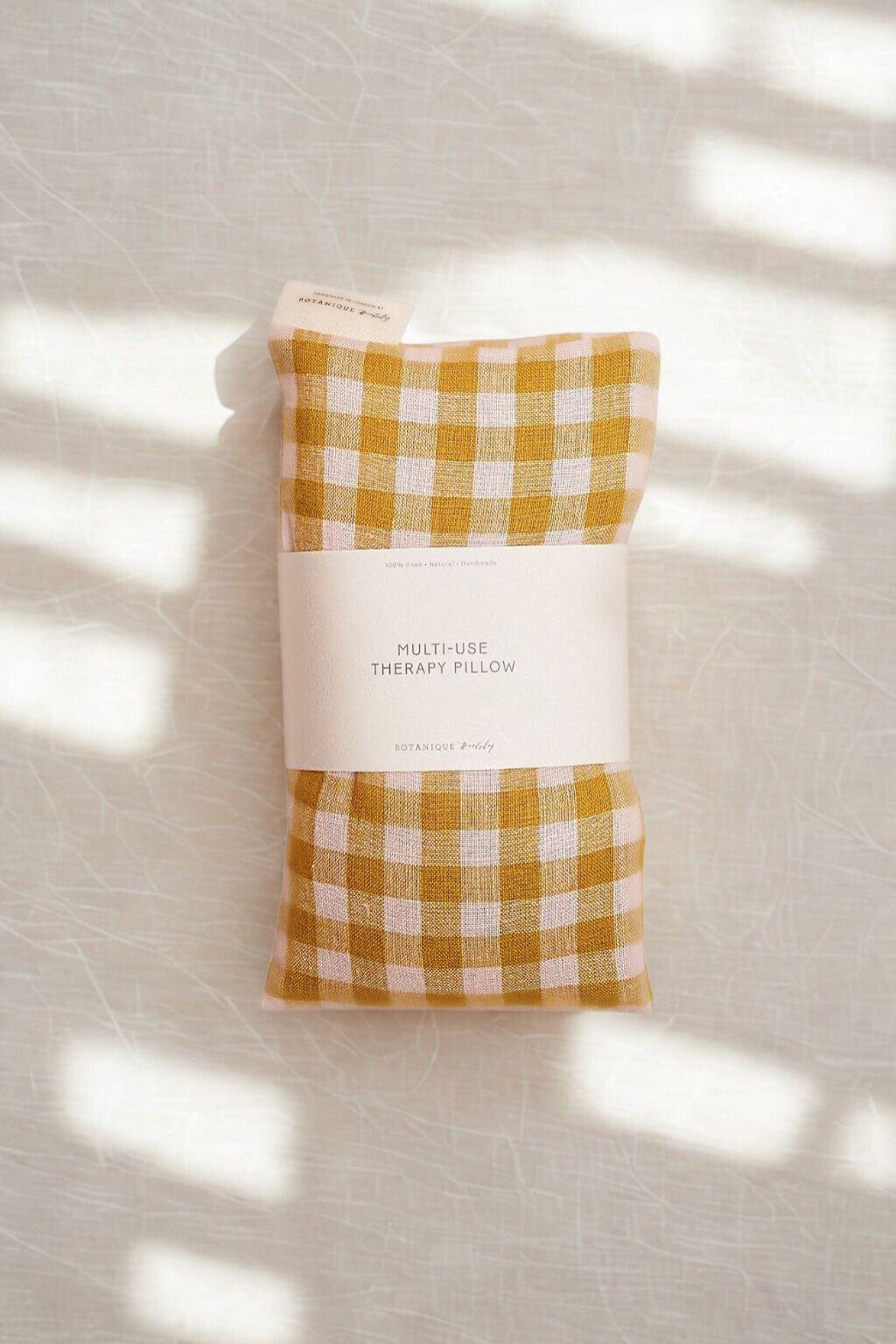 Yellow gingham lavender aromatherapy pillow with a textured  background with soft shadows