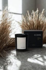 Cedar Luxury Candle beside dried grasses, sunlight streaming across the scene for a warm, natural look.