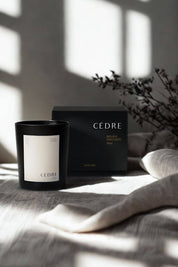 Cedar Luxury Candle and box on a linen surface, soft shadows of a window cast in the background.