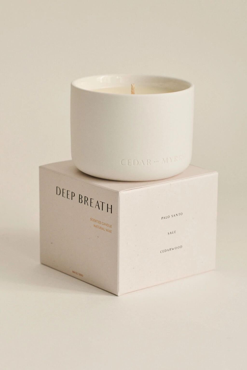 Deep Breath candle displayed atop its branded box, showing fragrance notes Palo Santo, Sage, and Cedarwood on the packaging.