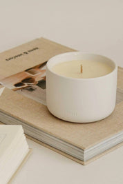 Unlit Deep Breath candle resting on top of a neutral-toned book stack, highlighting its minimal ceramic design.