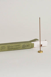 Open box of "Forest" Japanese incense sticks lying flat beside a brass incense holder, highlighting the neat arrangement of sticks inside the package.