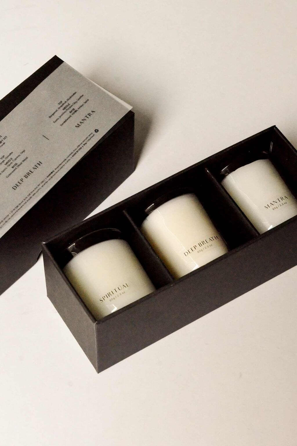 Open black gift box showcasing three mini candles labeled Spiritual, Deep Breath, and Mantra neatly arranged inside.