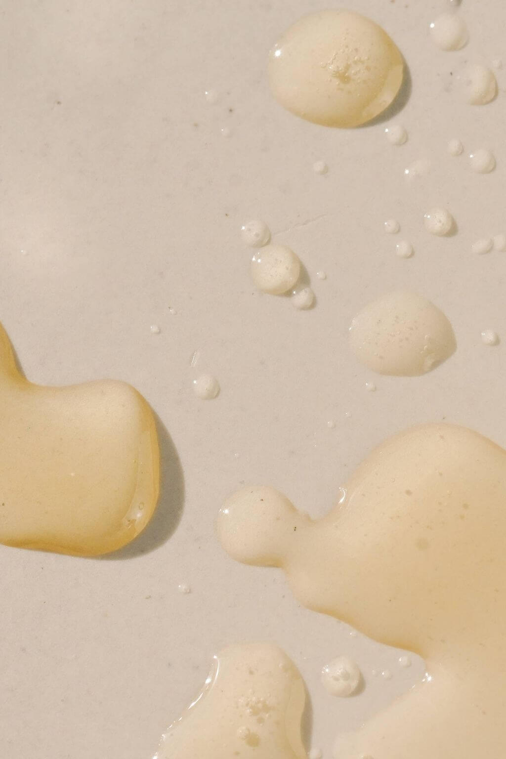 Golden drops of High Noon Body Oil on neutral background