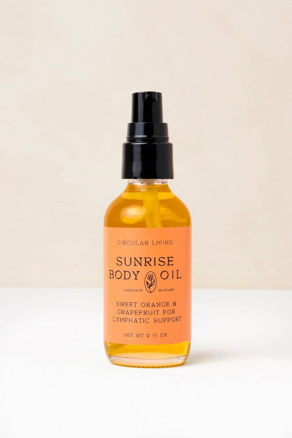 Sunrise Body Oil bottle with bright orange label against neutral background.