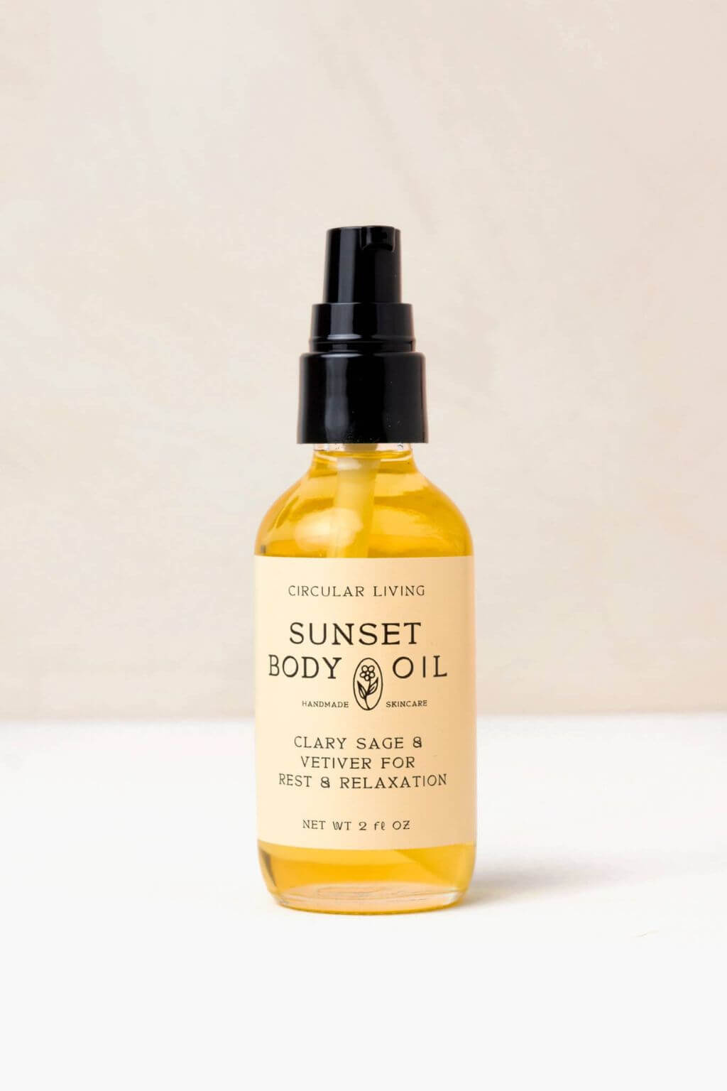Sunset Body Oil bottle with cream label against soft beige background.
