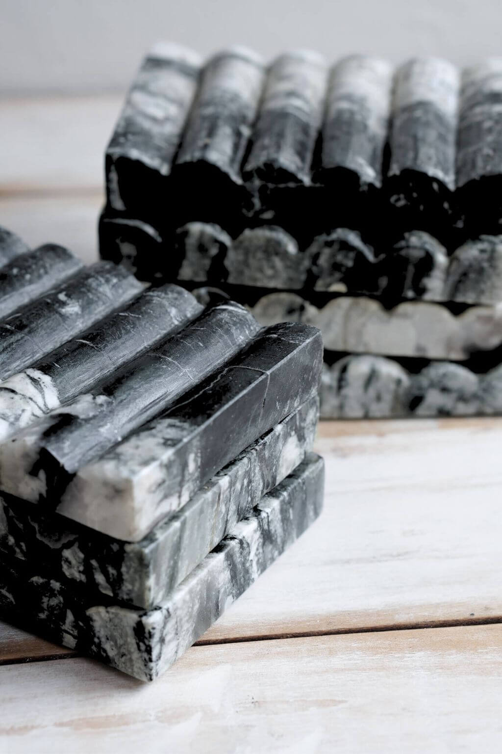 Close-up of Ridge Black Marble Soap Dishes stacked together, showing the ribbed surface and organic stone patterns.