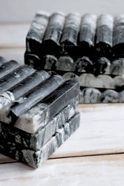 Close-up of Ridge Black Marble Soap Dishes stacked together, showing the ribbed surface and organic stone patterns.