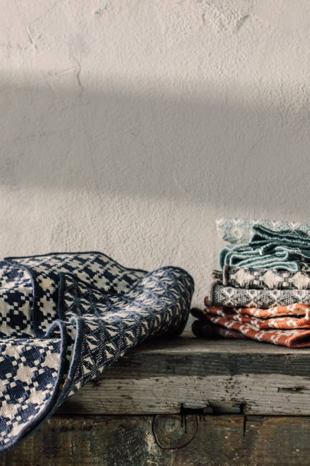 Stack of geometric patterned dishcloths on a wooden surface with a neutral background
