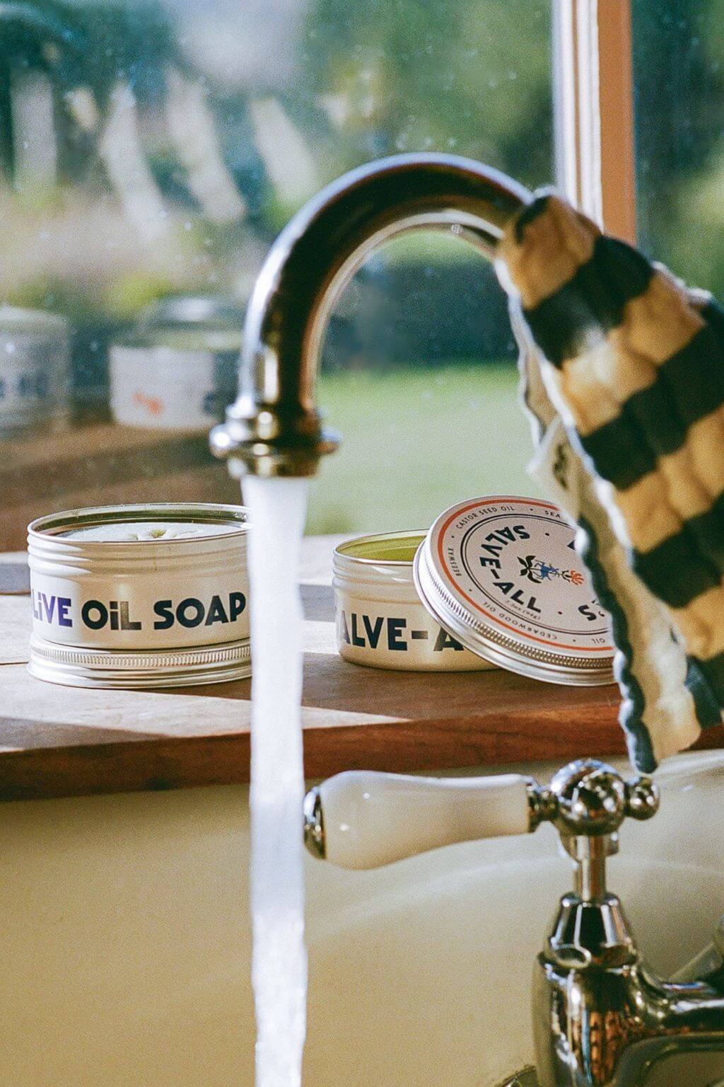 Olive oil soap set beside running faucet