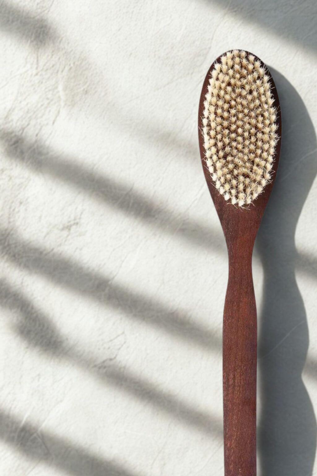 Dark Wooden bath brush with natural bristlea on a light background with shadows